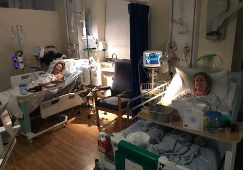 Two sisters in hospital bed next to each other.