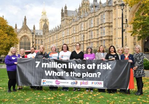 13 people holding a large banner outside of Parliament