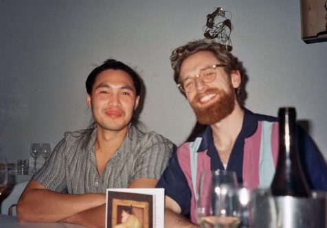 Two males, sat at a table, smiling for the camera