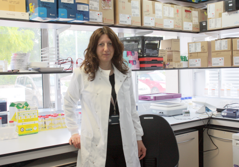 Female researcher, wearing a white lab coat, in her research lab.